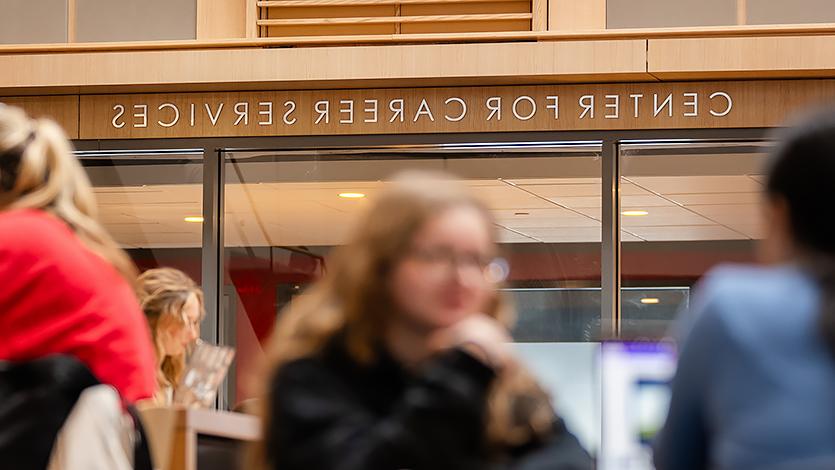 Image of the Center for Career Services sign with students sitting in the Dyson Center.